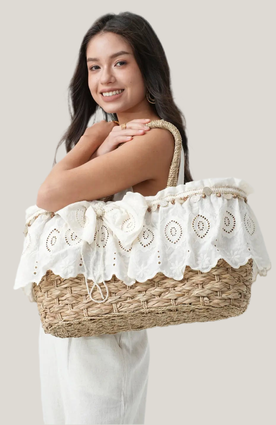 Woman holding a woven basket with lace trim against a plain background