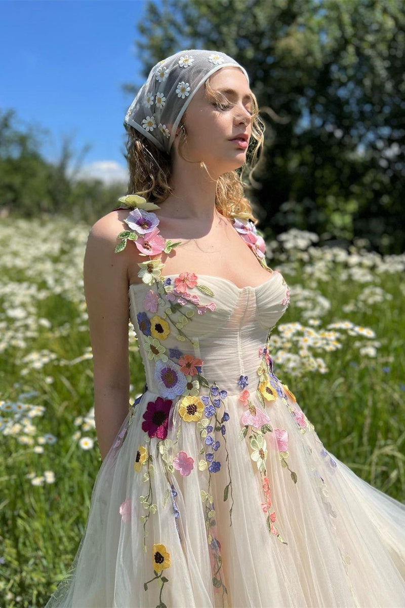Woman in a floral dress and headscarf standing in a field of flowers.