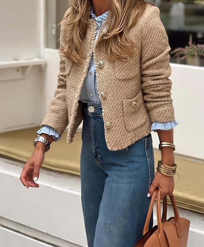 Person wearing a beige textured jacket with blue jeans and holding a brown handbag.