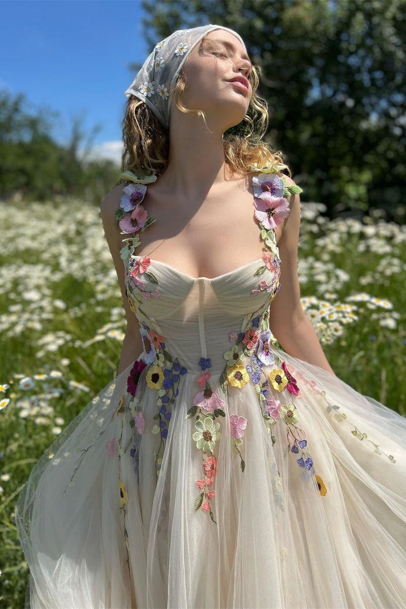 Woman in a floral dress standing in a field of flowers with a blue sky.